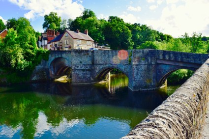 A pretty little lake an old style bridge.